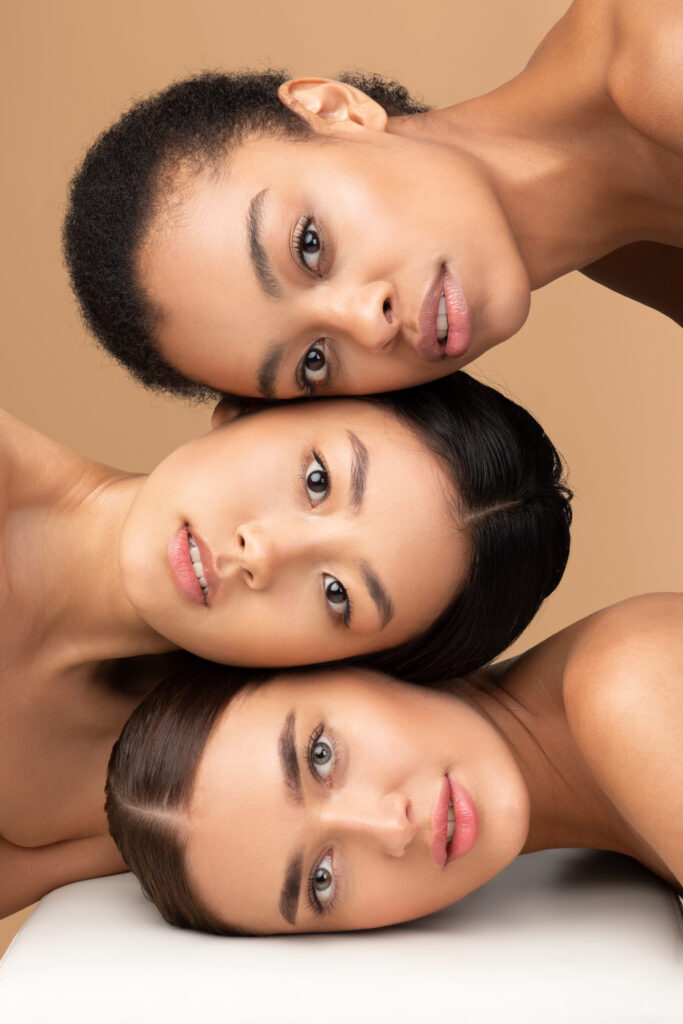 Home portrait of three attractive women looking at camera, beige background